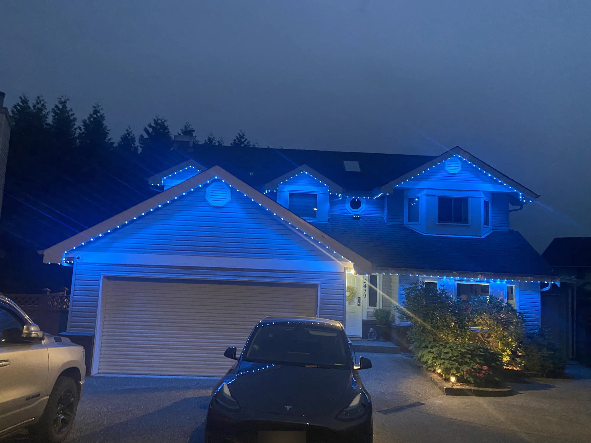 Vancouver home with blue permanent LED roofline lighting and warm white entrance lighting at dusk