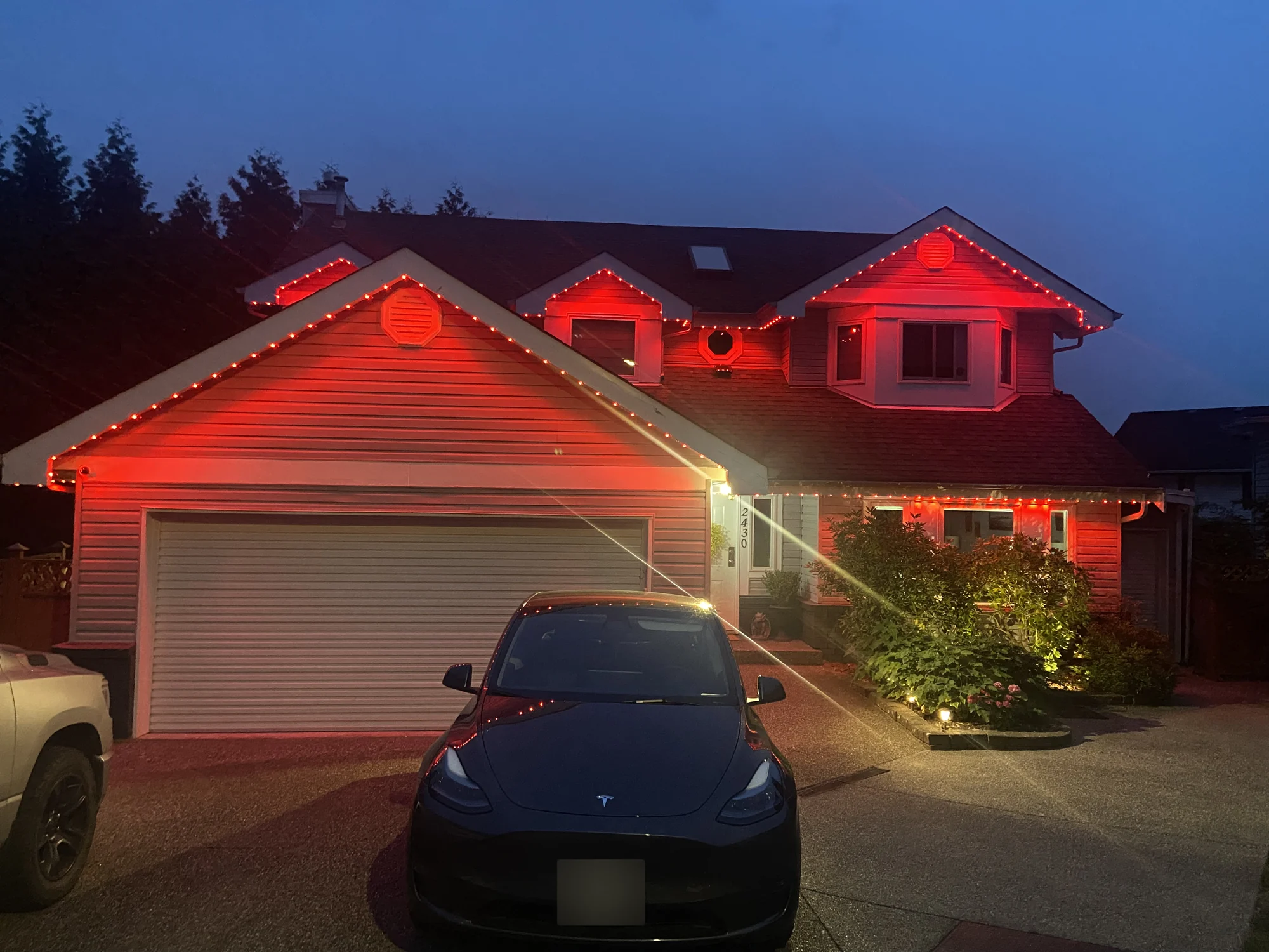 Vancouver home with vivid red permanent LED roofline lighting and warm white entrance lighting at dusk