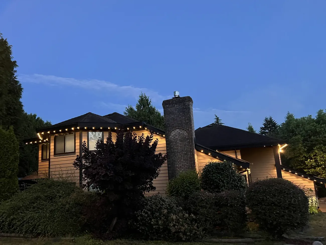 Home with warm white permanent LED roofline lighting at dusk